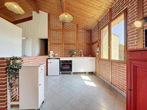 - une cuisine avec des appareils blancs et un mur en briques dans l'établissement Holiday Home Le Porteau by Interhome, à Pornic