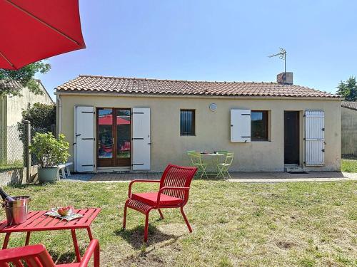 une chaise rouge et une table en face d'une maison dans l'établissement Holiday Home Le Porteau by Interhome, à Pornic