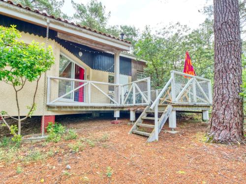 une maison avec une terrasse couverte et un escalier à côté d'un arbre dans l'établissement Holiday Home Golf Loisirs 22 by Interhome, à Lacanau-Océan