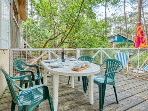 une table et des chaises blanches sur une terrasse en bois dans l'établissement Holiday Home Golf Loisirs 22 by Interhome, à Lacanau-Océan