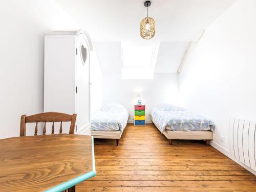 Cette chambre comprend 2 lits et une table en bois. dans l'établissement Holiday Home la Rivière by Interhome, à Cancale