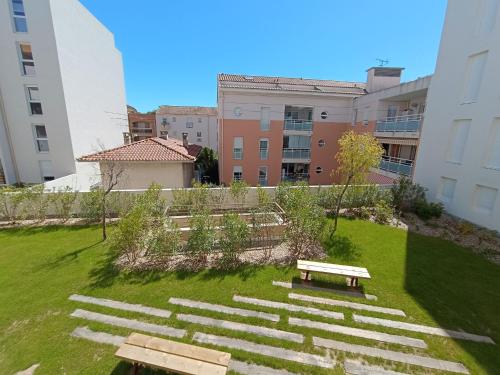 un parc avec des bancs, de l'herbe et des bâtiments dans l'établissement Apartment Villa Gabrielle by Interhome, à Fréjus
