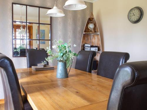 a dining room table with chairs and a vase with flowers at Holiday Home Quiraing Cottage by Interhome in Flodigarry
