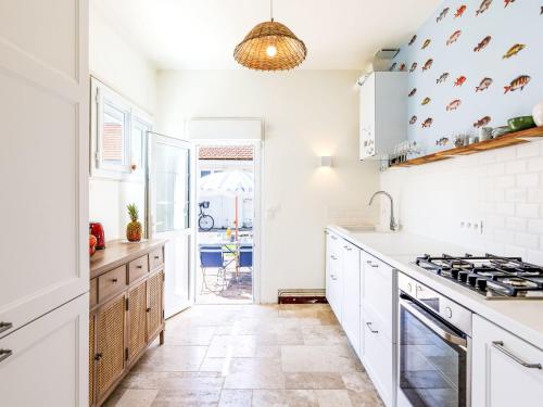 La cuisine est équipée de comptoirs blancs et de plaques de cuisson. dans l'établissement Holiday Home Charme de la Plage de Port Lin by Interhome, au Croisic
