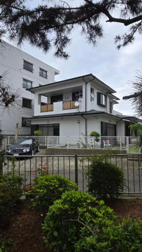 a white house with a car parked in front of it at 海の風 in Wakayama