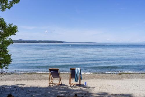 two chairs sitting on a beach next to the water at Sandy Beachfront, Hot Tub, Pet-friendly, Kayaking 