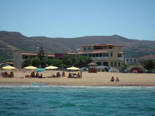 a group of people sitting on a beach with umbrellas at Gramvoussa Bay in Kissamos