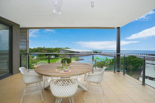 ダーウィンにあるTranquil Waterfront Lagoon Views BBQ & Cafesのバルコニーにテーブルと椅子が置かれたダイニングルーム