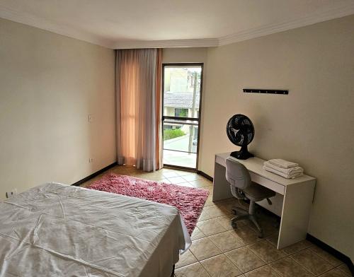 a bedroom with a bed and a desk and a window at Casa Grande 3 quartos, perto parque Barigui in Curitiba
