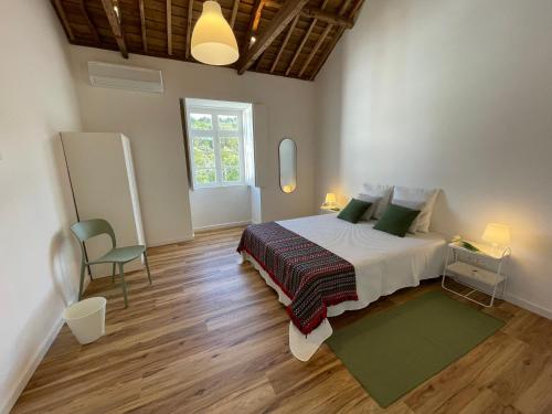 a bedroom with a bed and a chair and a window at Casa da Arquitectura - Texturas in Angra do Heroísmo