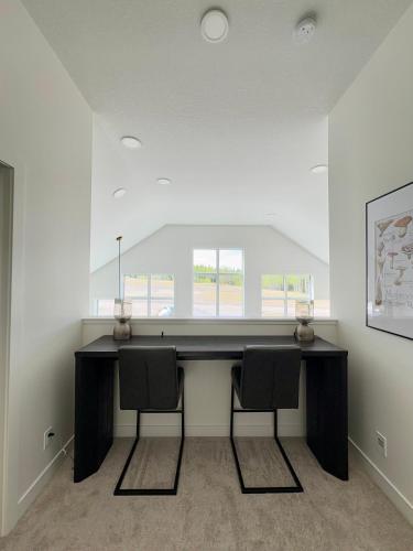 a desk with two chairs in a room with a window at The Lamp House in Nordegg
