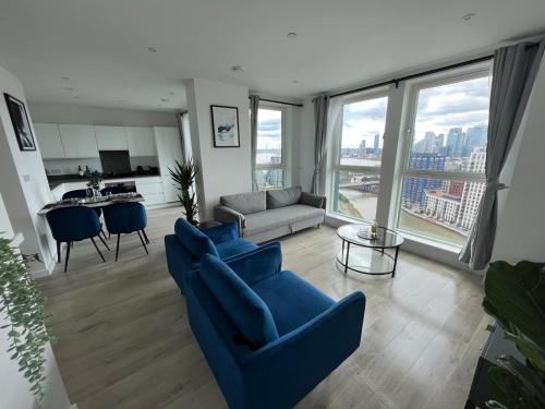a living room with blue chairs and a couch at Penthouse with O2 Arena View, Free Parking & Portable AC in London
