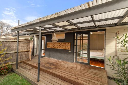 a pergola over a deck with a bed on it at Bright & Breezy Stay by the sea in Bonbeach