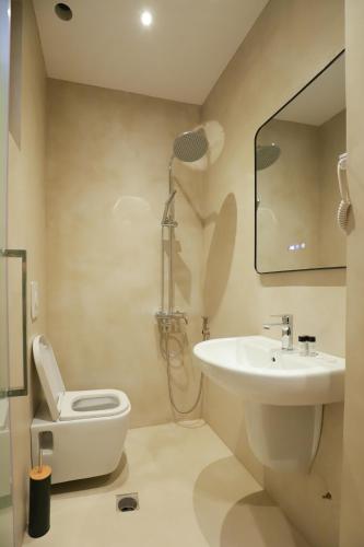 a bathroom with a sink and a toilet and a mirror at Hotel Relax City Center in Tirana