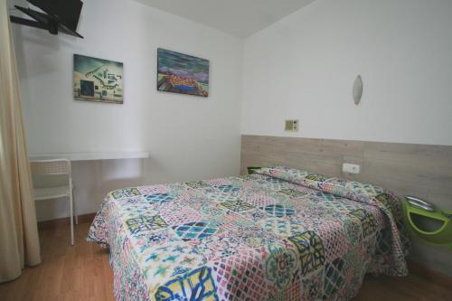 a bedroom with a bed with a colorful quilt on it at Rey Fernando in Santiago de Compostela