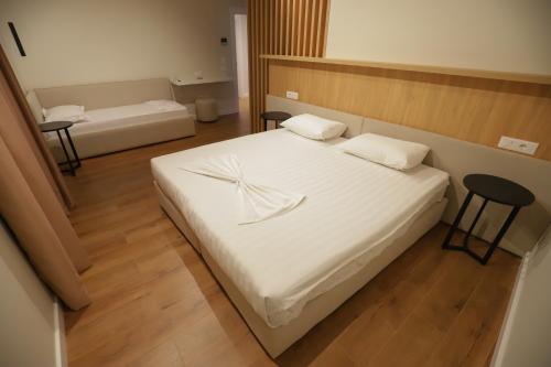 a bedroom with a large white bed with two chairs at Hotel Relax City Center in Tirana
