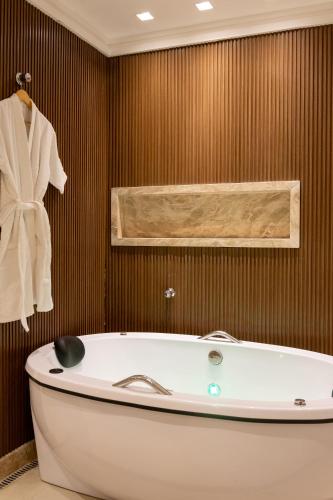 a bathroom with a tub and a towel on a wall at Aira Hotel in Sobral