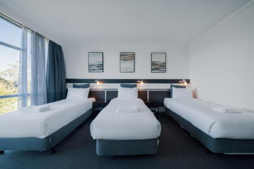 three beds in a room with a window at The Select Inn Ryde in Sydney
