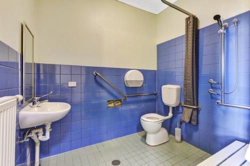 a blue tiled bathroom with a toilet and a sink at YHA Blue Mountains Katoomba in Katoomba