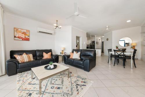 a living room with black leather furniture and a table at Ideal CBD Location with Harbour Views Pool Gym & BBQ in Darwin