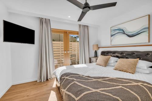 a bedroom with a large bed and a flat screen tv at Bellvilla - Bluebonnet Suite in Merimbula