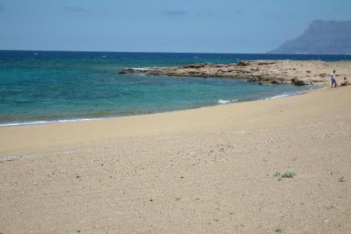 a beach with people walking on the sand and the ocean at Gramvoussa Bay in Kissamos