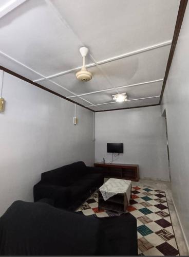 a living room with a black couch and a tv at HOMESTAY DWASih in Kuantan