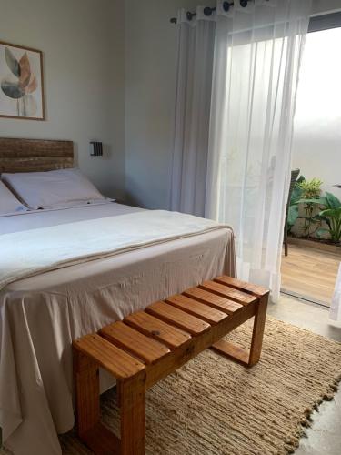 a bedroom with a bed and a wooden bench at Sattva Pousada in Pirenópolis