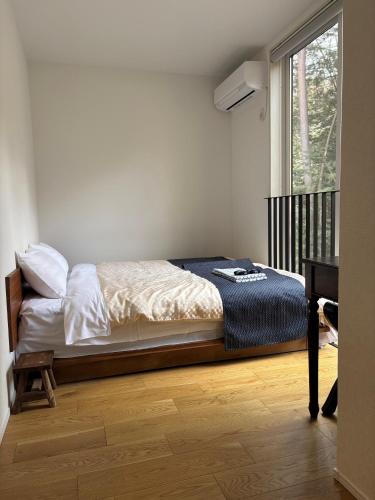 a bedroom with a bed and a desk and a window at 富士の星空 エフジェイフォレスト in Fujikawaguchiko
