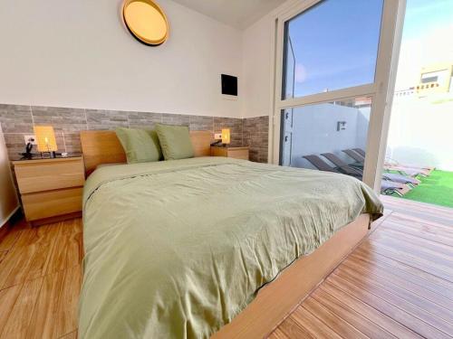 a bedroom with a large bed with a large window at Bungalow with sea view in Caleta De Fuste