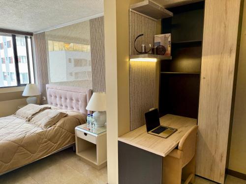 a bedroom with a bed and a laptop on a desk at Akros Suite Quito in Quito