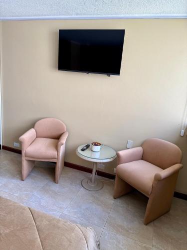 a room with two chairs and a table and a tv at Akros Suite Quito in Quito