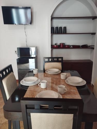 a dining room table with four chairs and plates on it at Nuevo departamento en el centro de Coatepec in Coatepec