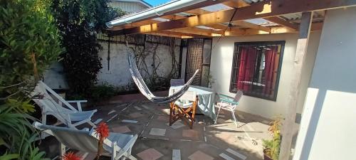 a patio with white chairs and a table and chairs at Cabaña Los Corsarios in El Quisco