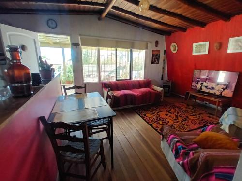 a living room with red walls and a table and a couch at Cabaña Los Corsarios in El Quisco