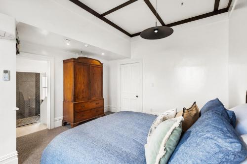 a bedroom with a blue bed and a wooden dresser at Historic Waterfront Apartment - Ashton House in Napier