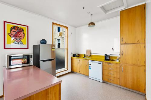a kitchen with a refrigerator and wooden cabinets at Historic Waterfront Apartment - Ashton House in Napier