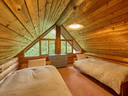 ein Schlafzimmer mit zwei Betten in einer Blockhütte in der Unterkunft ルネス軽井沢-高原の貸切コテージでBBQ and 焚火を満喫- in Tsumagoi