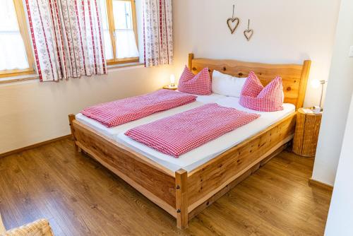 a bedroom with a large wooden bed with pink pillows at Gästehaus Hinterponholz in Ramsau