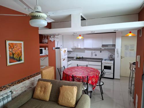 cocina y comedor con mesa roja y sillas en Departamento Eutico, en Villa Carlos Paz