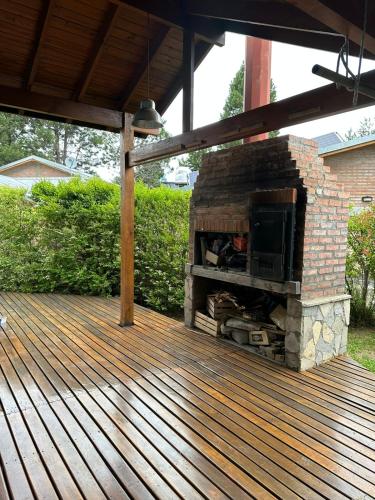 a stone fireplace on a deck with a roof at Aromas de Montaña II in Junín de los Andes