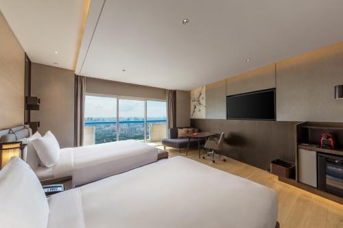 a hotel room with two beds and a flat screen tv at Swissotel The Stamford Singapore in Singapore