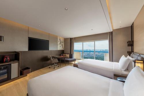 a hotel room with two beds and a flat screen tv at Swissotel The Stamford Singapore in Singapore