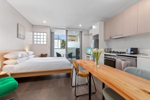 a bedroom with a bed and a kitchen with a table at Bright Studio with Balcony near Coogee Beach in Sydney