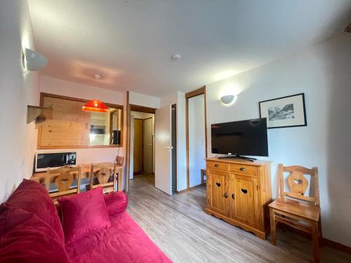Il comprend un salon doté d'un canapé rouge et d'une télévision à écran plat. dans l'établissement Confortable studio pour 4 avec TV et casier à ski, proche centre et pistes - FR-1-411-984, à Val dʼIsère