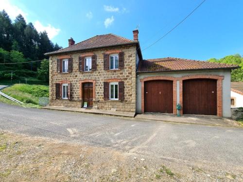 a brick house with two garage doors on a street at Charmant gîte pour 6 personnes à Néronde - FR-1-496-357 
