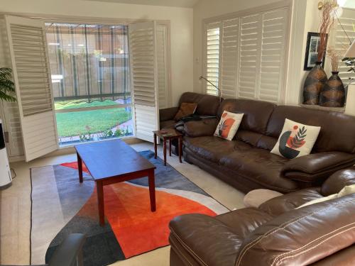 a living room with a leather couch and a table at HOME STAY on HIGH King Bed -- Private Home with Private Bathroom in Swan Hill