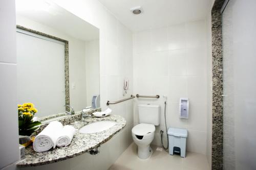 a white bathroom with a sink and a toilet at Green Hotéis in Cabo Frio