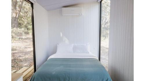 a bed in a room with a large window at Sunset Vine at Wonganella Estate 1 by Tiny Away in Bobs Farm