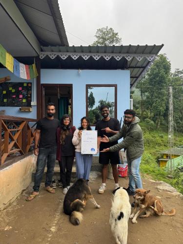 a group of people standing in front of a house holding a check at The Blue House in Pelling